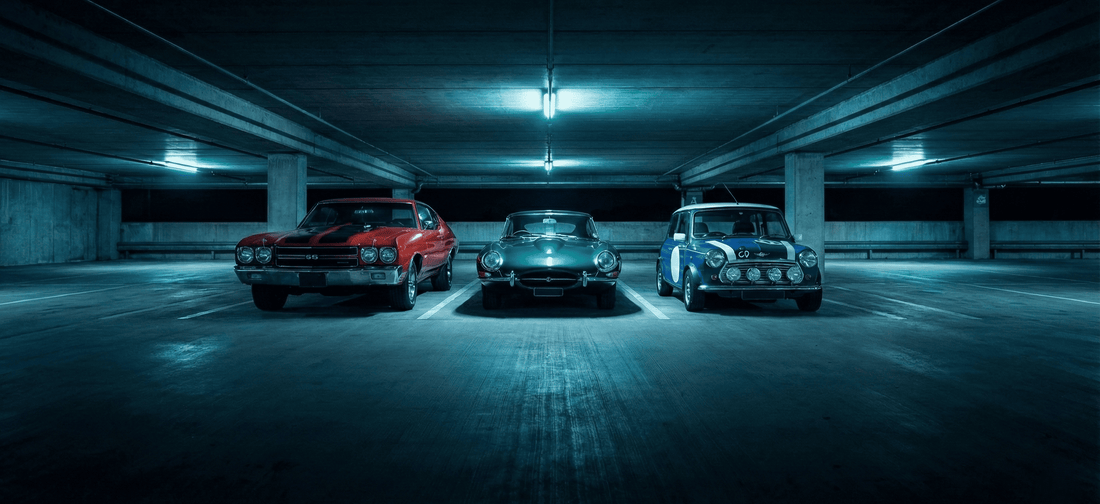 Trois voitures de collection (Chevrolet Chevelle, Jaguar Type E, Mini Cooper) stationnées dans un parking souterrain - cibles fréquentes de vol