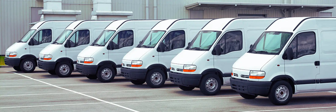 Flotte d'utilitaires blancs garés en rang sur un parking professionnel