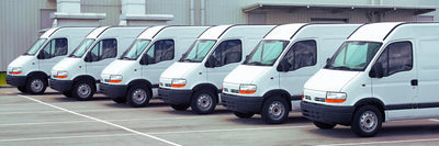 Flotte d'utilitaires blancs garés en rang sur un parking professionnel