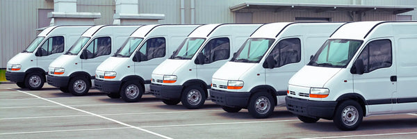 Flotte d'utilitaires blancs garés en rang sur un parking professionnel