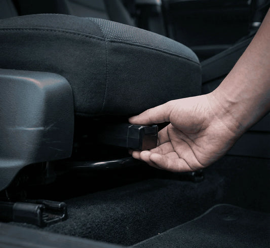Main installant un traceur GPS magnétique compact sous le siège conducteur d'une voiture